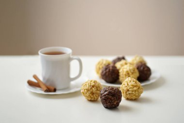       chak chak kekleri tatlı tatlı yuvarlak şekilli tabakta, birkaç parça masada, bir fincan tarçınlı çay tabakta                         