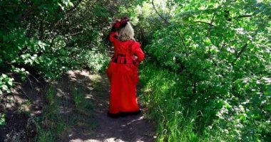 Kırmızı tarihi kostümlü sarışın kadın. Eski moda. Gizli pencereden bakıyor.