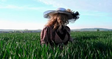 Tarlada büyük şapkalı, tarihi kostümlü bir kadın Pandoras kutusunu açıyor.