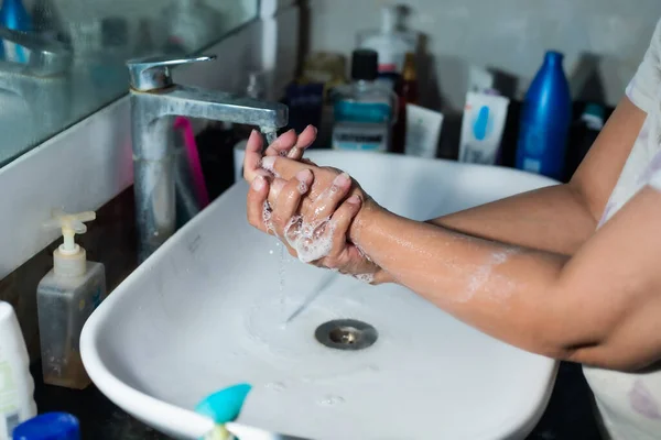 Yetişkin bir kadın, Coronavirus 'la savaşmak için lavabonun ve lavabonun altındaki sabunla ellerini ve kollarını düzgün bir şekilde yıkıyor. Banyo konsolu, arka planda bir sürü ürünle el yıkama, metin eklemek için yer