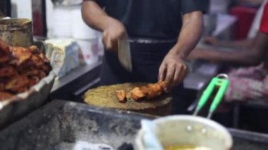 Jama Mescidi, Eski Delhi 'deki Aslam Chicken' da ünlü tereyağlı tandır tavuğu. Büyük bir bıçakla et doğrayan bir adam. Tavuğu satırla parçalara ayırmak. Ramazan Bayramı yemeği 2020.