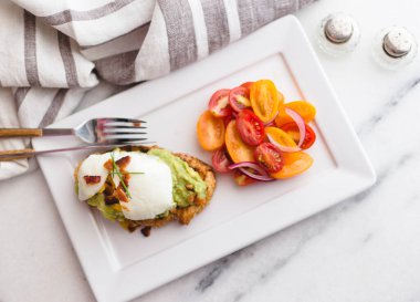 Brunch için mermer bir tepside haşlanmış yumurta ve domates salatalı avokado tostu..