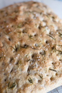 Beyaz bir yüzey ve sarı mutfak havlusu üzerine biberiye Focaccia..