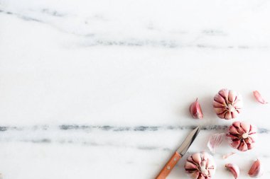 Sarımsak ve bıçak beyaz mermer yüzeyde.