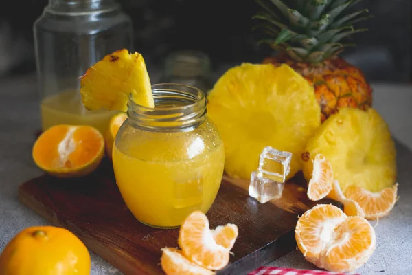 Mandalina suyu ananas, koyu arkaplan ve kendi meyvesiyle bir tarafta.