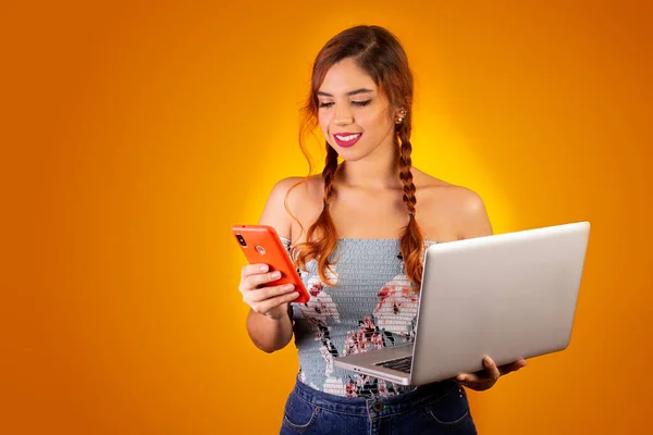 Cep telefonu ve bilgisayar kullanan gülümseyen bir kadın. sarı arkaplan
