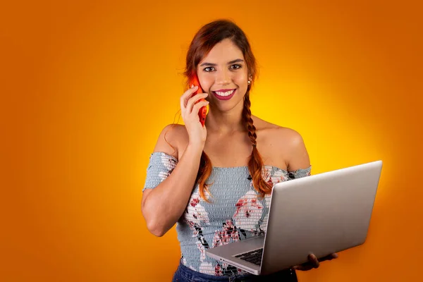 Cep telefonu ve bilgisayar kullanan gülümseyen bir kadın. sarı arkaplan