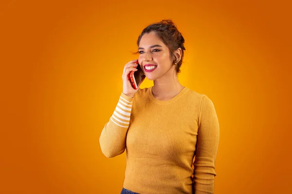 Sarı arka planda cep telefonu kullanan ve gülümseyen bir kadın