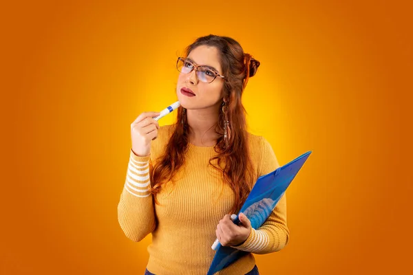 Öğretmen kalem ve klasörle düşündü. Sarı arkaplan