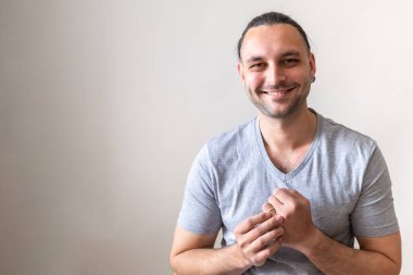 Mutlu genç koca gülümsüyor ve alyansını sol elinde beyaz arka planda tutuyor.