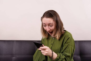 Siyah koltuktaki kız telefon ekranına bak. Piyango kazanmış gibi çığlık atıyor.