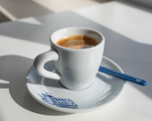 Espresso v bílém šálku s modrým potiskem ráno se stíny z okna