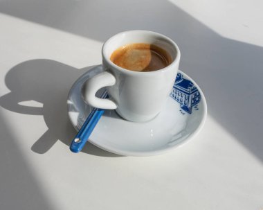 Sabahları beyaz bir fincanda Espresso. Pencereden yansıyan gölgeler.