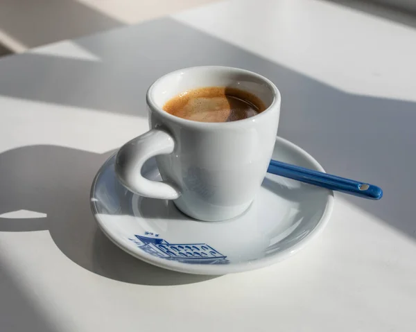 窓から影が付いている朝の青いプリントの白いカップの中のエスプレッソ — ストック写真