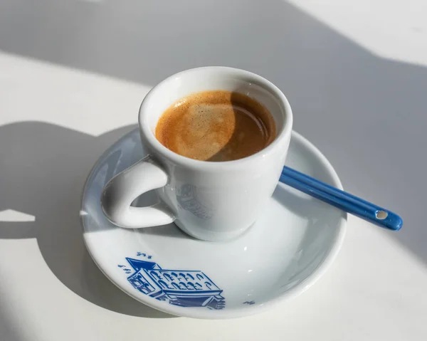 Espresso in a white cup with a blue print in the morning with shadows from the window