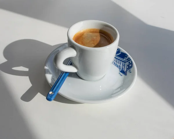 Espresso in a white cup with a blue print in the morning with shadows from the window