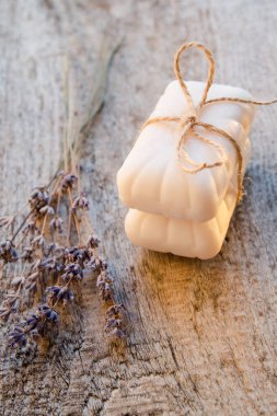 Kahverengi dantelli iki beyaz sabun kulesi ve ahşap arka planda kurutulmuş lavanta buketi.