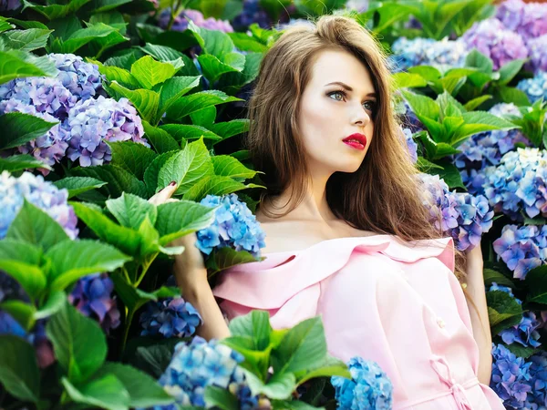 Mooi meisje in de hydrangea bloemen — Stockfoto