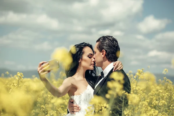 Casamento casal beijo no campo flores amarelas — Fotografia de Stock