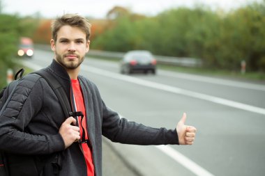 Genç adam otostop çekiyor.