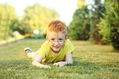 Çimenlerin üzerinde bardaklarda Kızıl saçlı erkek mutlu bebek