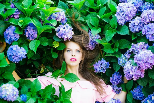 Mooi meisje in de hydrangea bloemen — Stockfoto