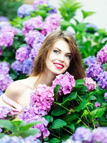 Hübsches lächelndes Mädchen in Hortensienblüten — Stockfoto