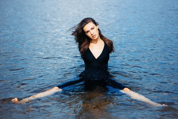 Sexy chica joven se sienta en el agua — Foto de Stock
