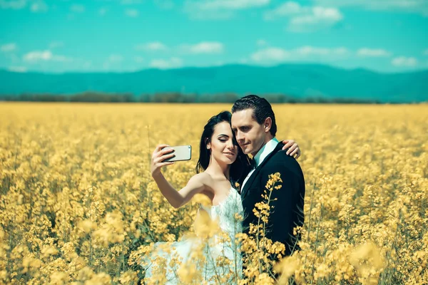 Bruidspaar in veld gele bloemen — Stockfoto