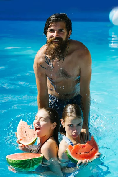 Vrouwen en man met watermeloen in zwembad — Stockfoto