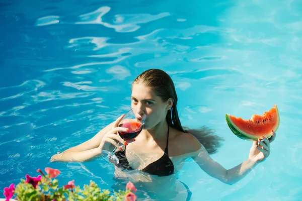 Vrouw met watermeloen en wijn in zwembad — Stockfoto