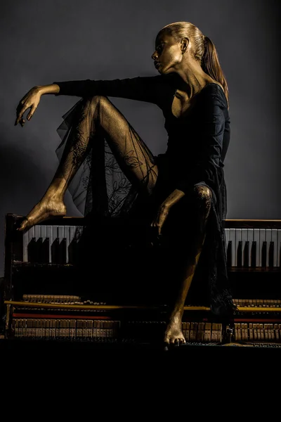 Sexy hübsche goldene Frau auf dem Klavier — Stockfoto