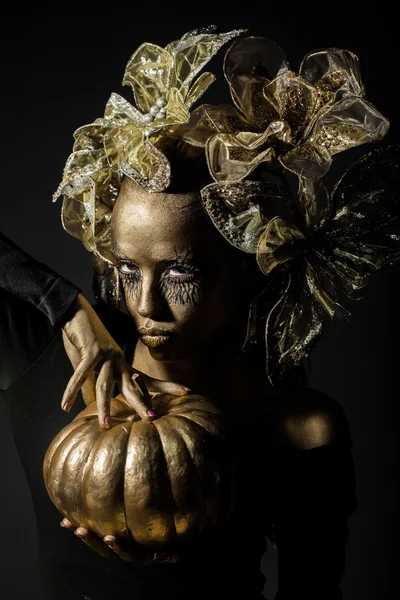 Gouden vrouw met Halloween pompoen — Stockfoto