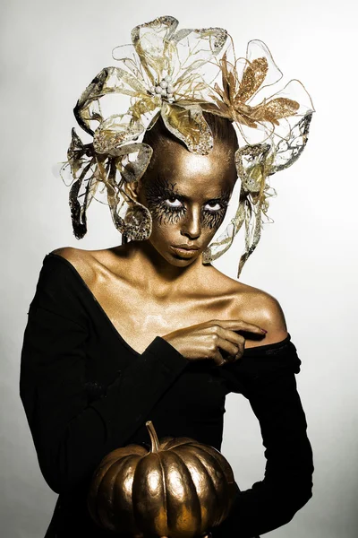 Gouden vrouw met Halloween pompoen — Stockfoto