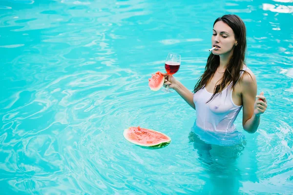 Ragazza fumatrice con anguria e vino in piscina — Foto Stock