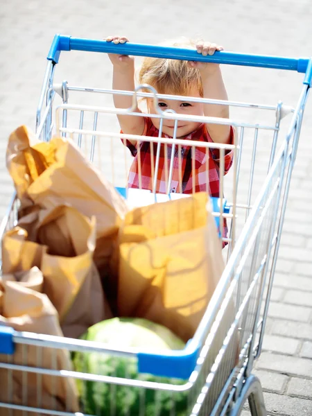 Netter Junge schiebt Einkaufswagen — Stockfoto