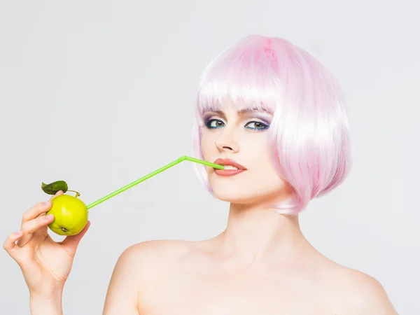 Bonita chica en peluca rosa con manzana verde — Foto de Stock