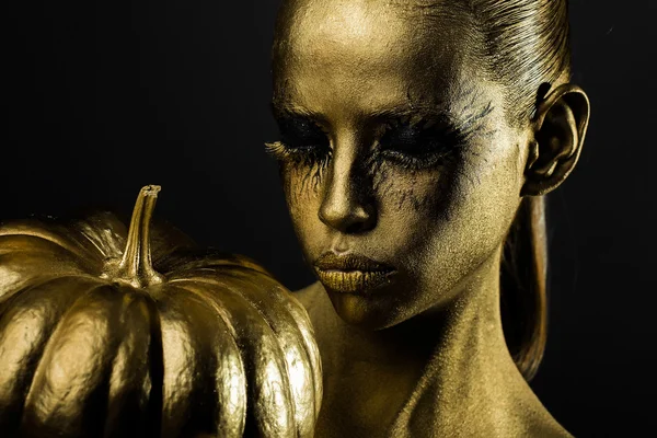 Mujer dorada con calabaza de halloween —  Fotos de Stock