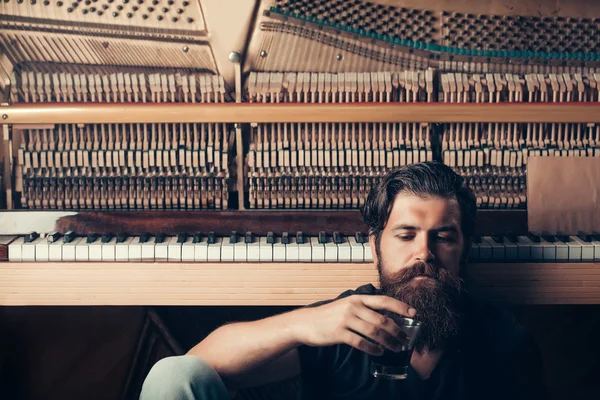 Bearded man with glass near wood piano — Stock Photo, Image