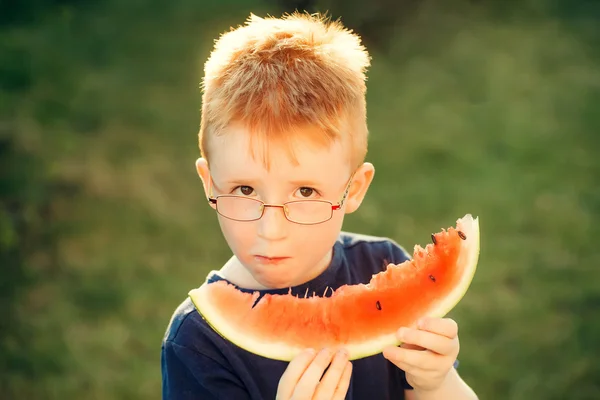 Menino feliz com cabelo vermelho em óculos comendo melancia — Fotografia de Stock