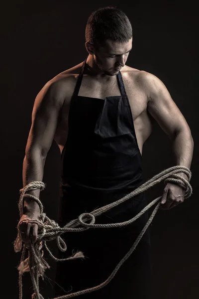 М'язистий чоловік в фартуху з мотузкою — стокове фото