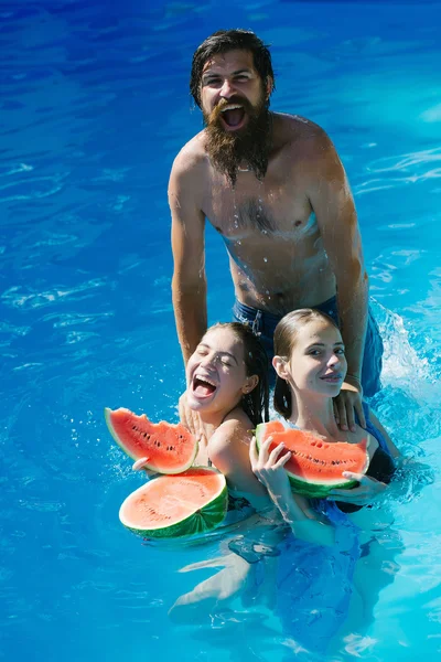 Vrouwen en man met watermeloen in zwembad — Stockfoto