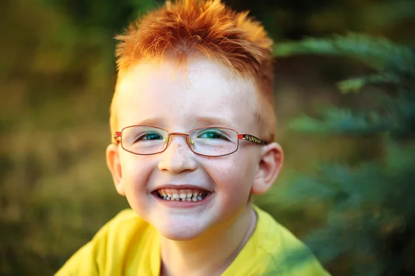 Счастливый мальчик с рыжими волосами в очках — стоковое фото