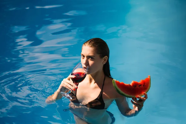 Mujer con sandía y vino en la piscina — Foto de Stock