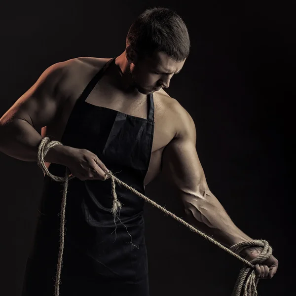 Muskulöser Mann in Schürze mit Seil — Stockfoto