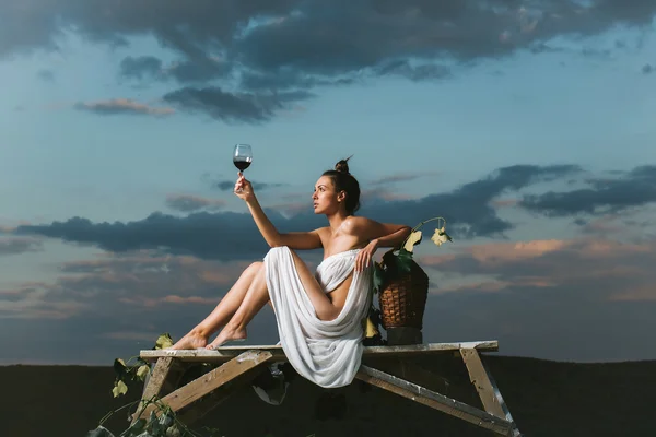 Красивая женщина с вином над небом — стоковое фото