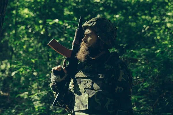 Skäggig soldat med bössan i skogen — Stockfoto