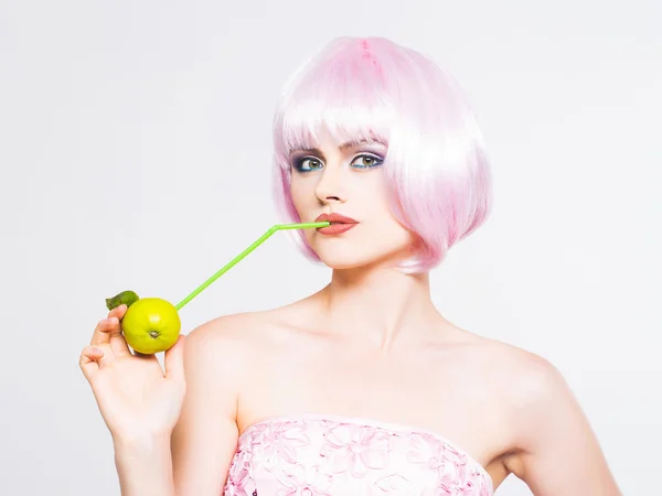 Bonita chica en peluca rosa con manzana verde — Foto de Stock