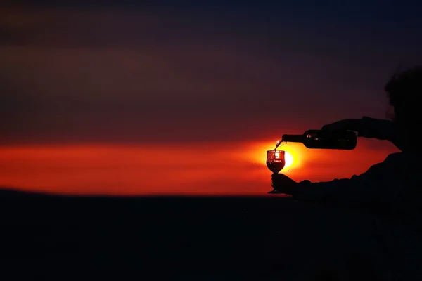 Hands pouring wine on sunset — Stock Photo, Image