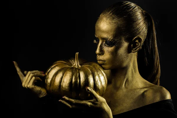 Gouden vrouw met Halloween pompoen — Stockfoto